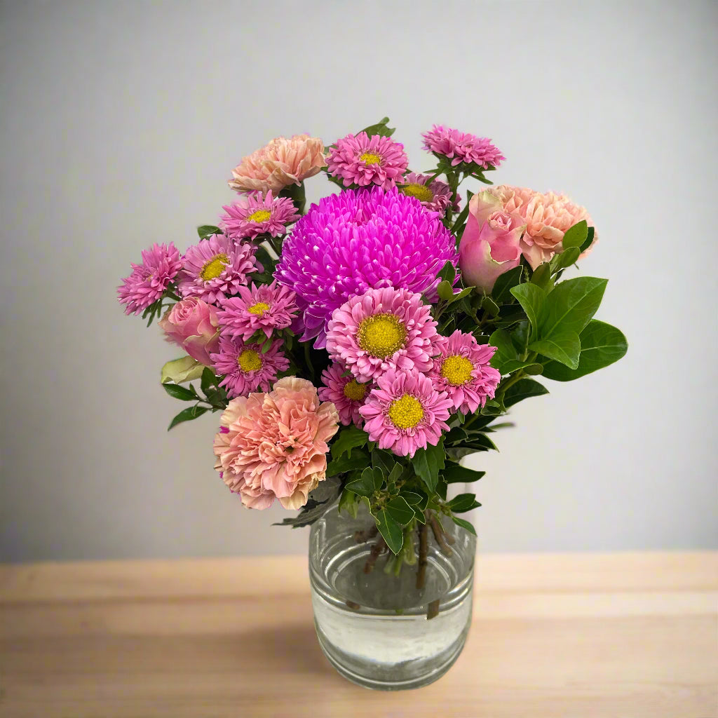 Pink winter flowers with green foliage in compact modern arrangement