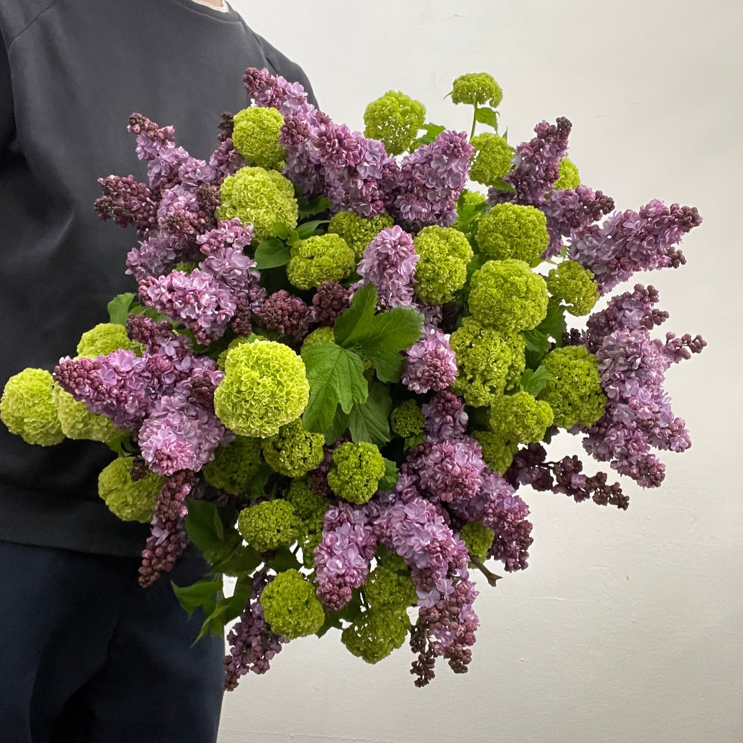 Large rounded lilac and green bouquet featuring viburnum snowball and purple blooms, made by Adam The Flower Man in Sandringham.