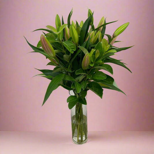 Oriental lilies with viburnum foliage, wrapped in signature paper and ribbon, creating a fresh and elegant bouquet.