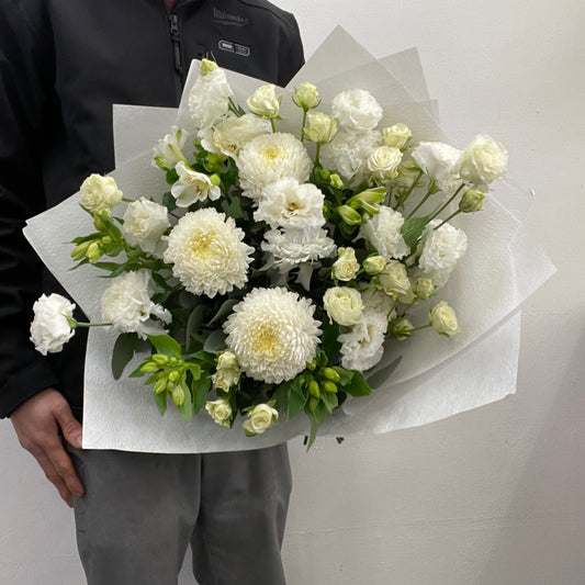 Bouquet of white flowers held by a person against a plain background