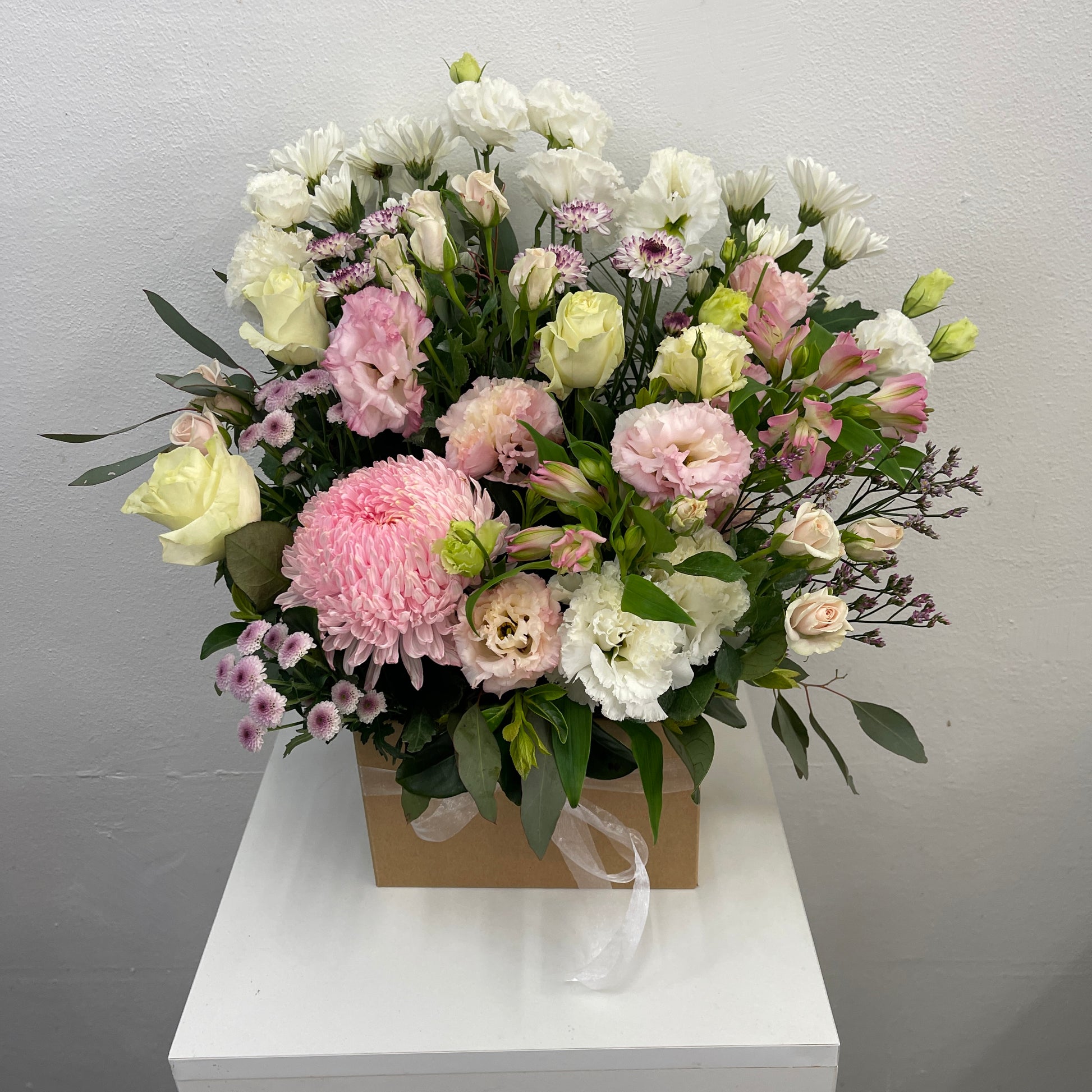 Bouquet of flowers in a box on a white surface with a gray background
