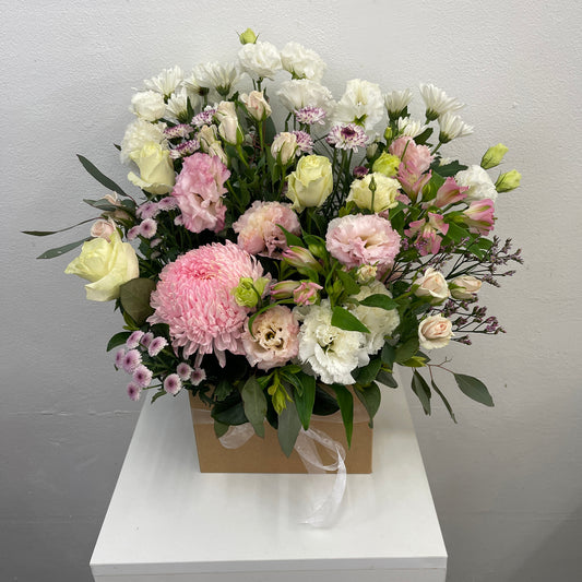 Bouquet of flowers in a box on a white surface with a gray background