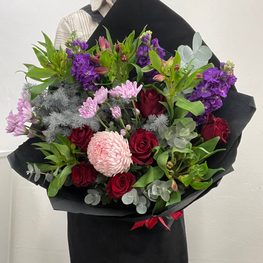 Bouquet of flowers wrapped in black paper against a white background