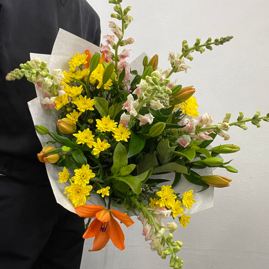 Rounded bouquet featuring snapdragons, orange LA lilies, yellow chrysanthemums, and viburnum foliage, part of the Spring Limited Collection 2025 by Adam The Flower Man.
